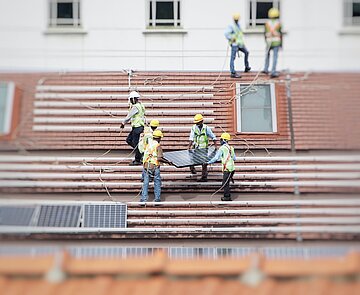 Menschen auf einem Dach, beim Installieren von Solarpaneelen